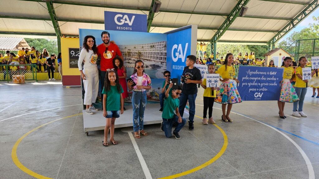 Crianças e voluntários em evento dos Amigos do Bem, com banner da GAV Resorts e cartazes de agradecimento pela geração de renda para o sertão.