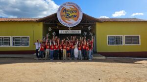 Grupo de voluntários em frente ao Centro de Transformação Amigos do Bem, Unidade Pernambuco, celebrando com as mãos erguidas.