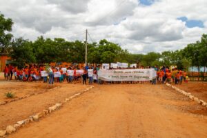 Crianças e moradores seguram faixas de boas-vindas em Inajá, terra da esperança, durante evento comunitário.